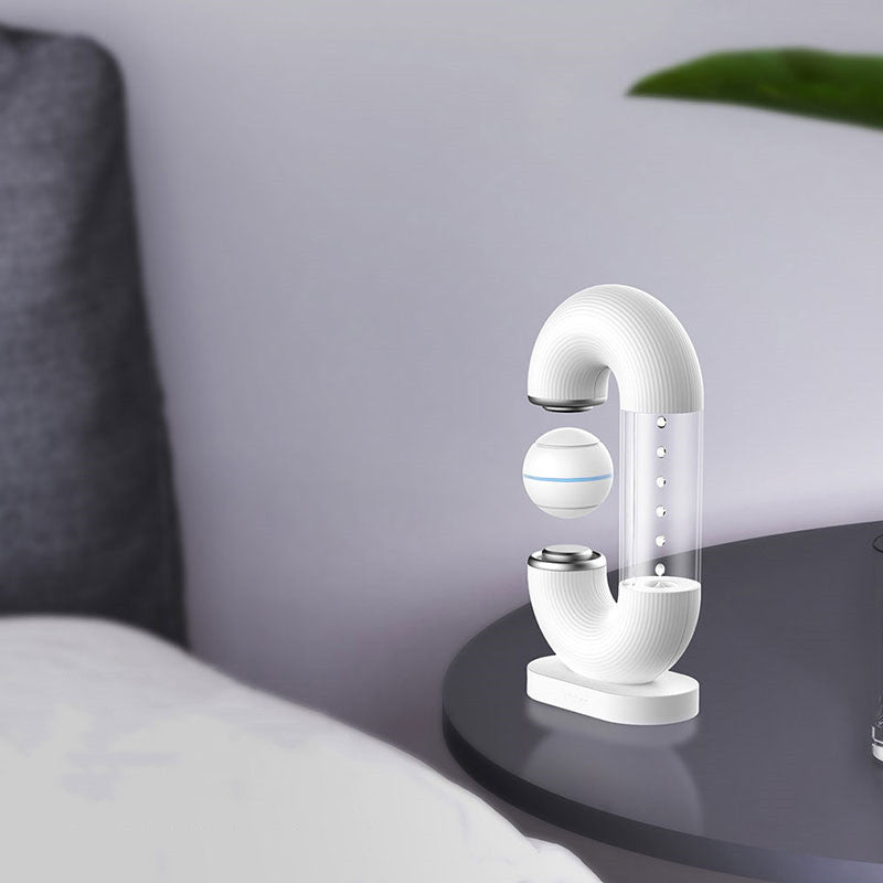 SuspendAir™: Whisper-Quiet Magic Water Droplet Air Purifier – Purifies as it Levitates showing levitating ball and droplets white next to a bed