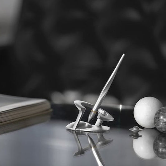 Floatnik™ pen on a shiny desk next to 2 balls and a book